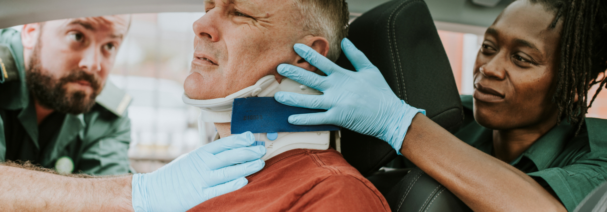 Paramedics securing a man's neck brace inside a vehicle following an accident, highlighting the severe injuries that lead to complex damages and potential medical negligence claims.